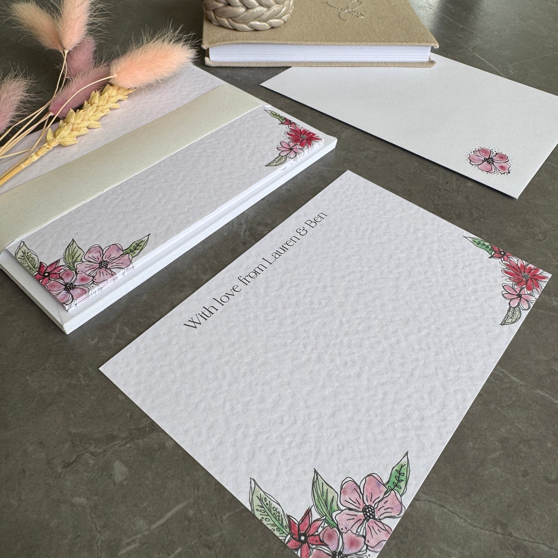Textured white correspondence cards with pink floral motifs in the bottom corners and a name personalised at the top in a pretty modern font