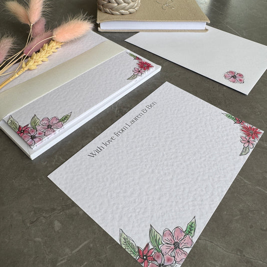 Textured white correspondence cards with pink floral motifs in the bottom corners and a name personalised at the top in a pretty modern font