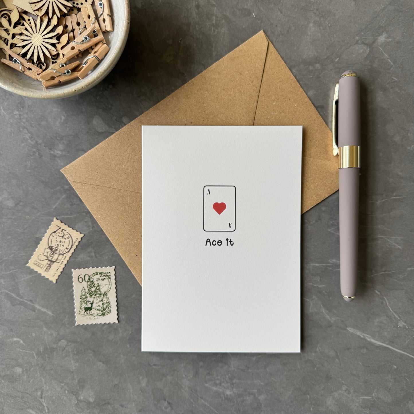White greeting card with illustration of an ace of hearts playing card and the words "Ace it" in a playful font